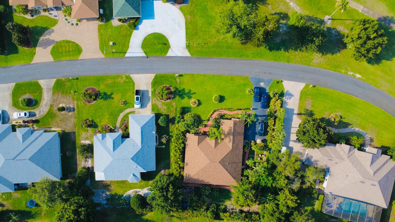 Aerial shot of a suburban neighborhood showcasing houses, driveways, and green lawns.