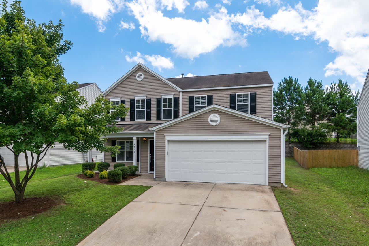 Charming two-story suburban home with green lawn, two-car garage, and blue sky.