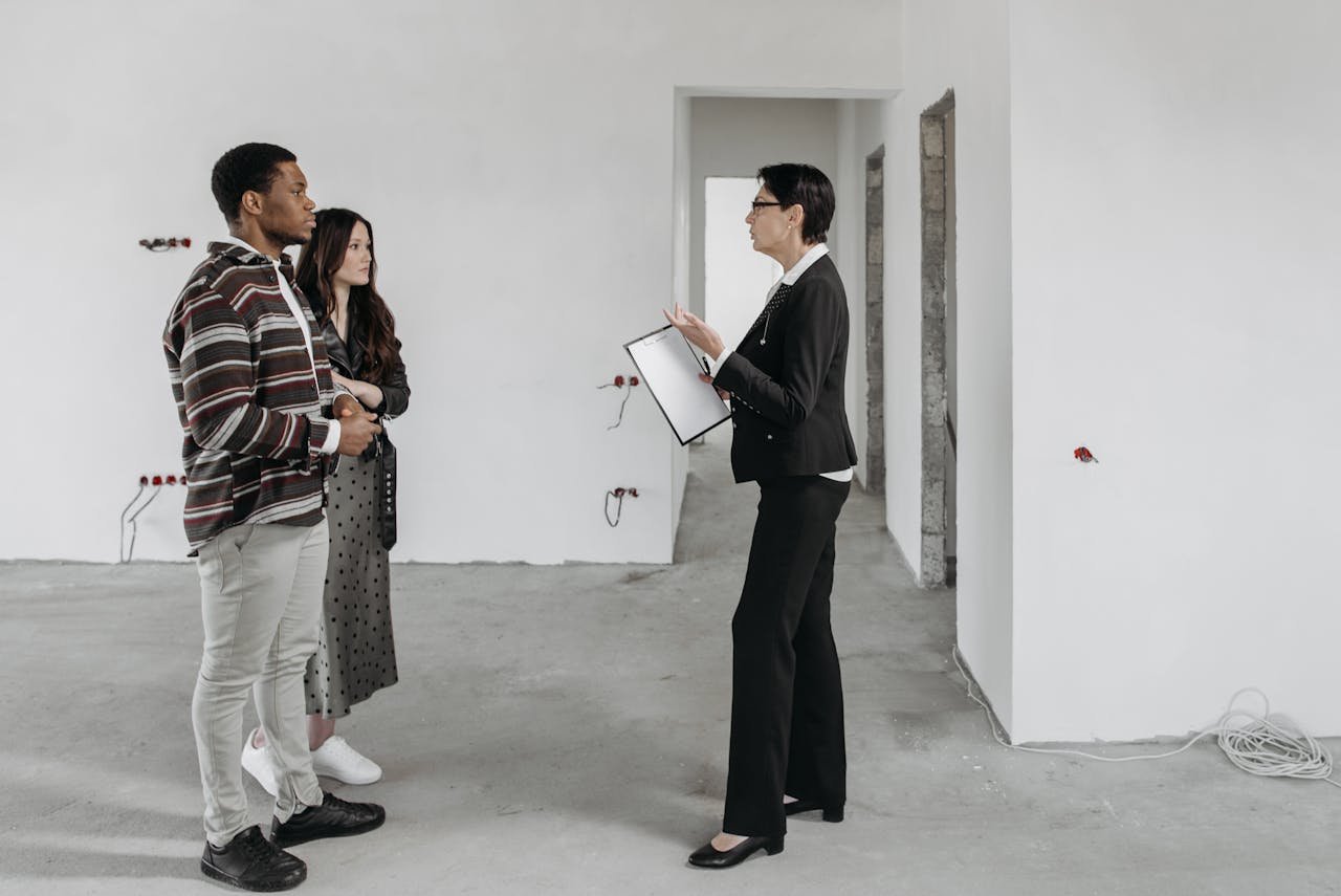 Real estate agent showing a house to a couple in a newly built home interior.