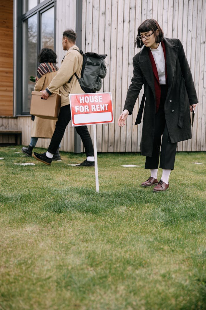 A group of adults inspecting a house for rent sign outside an apartment building while moving in.